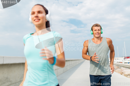 Image of couple with headphones running outdoors