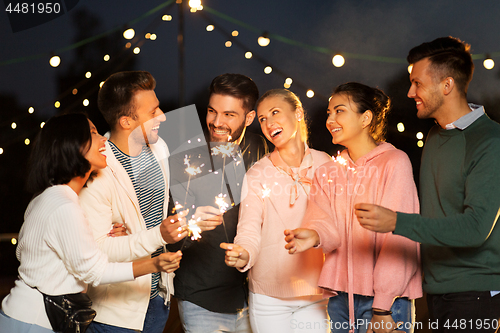 Image of happy friends with sparklers at rooftop party