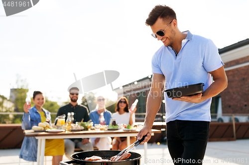 Image of man cooking meat on bbq at rooftop party