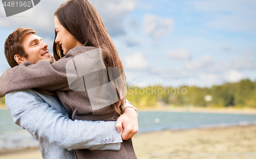 Image of happy young couple hugging over autumn beach