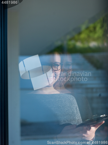 Image of Woman using tablet at home by the window