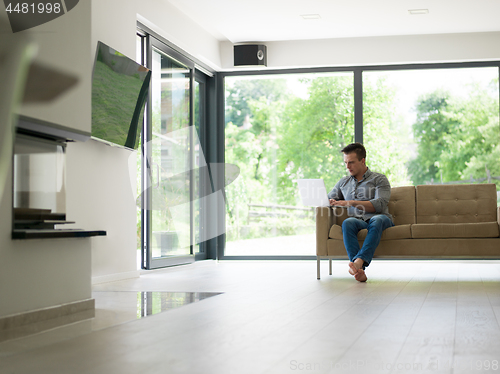 Image of Man using laptop in living room