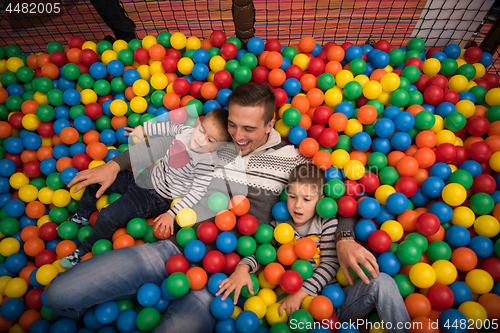 Image of Young dad with kids in a children\'s playroom