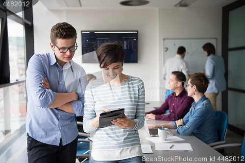 Image of Two Business People Working With Tablet in office