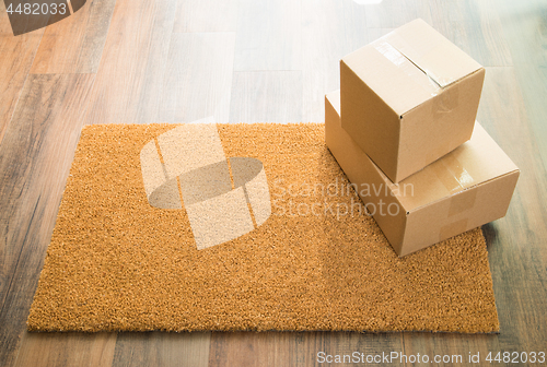 Image of Blank Welcome Mat On Wood Floor With Shipment of Boxes