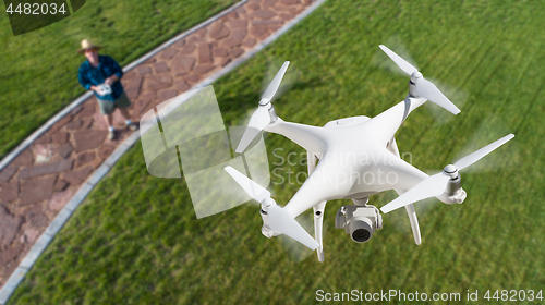 Image of Drone Quadcopter (UAV) In Air Above Pilot With Remote Controller