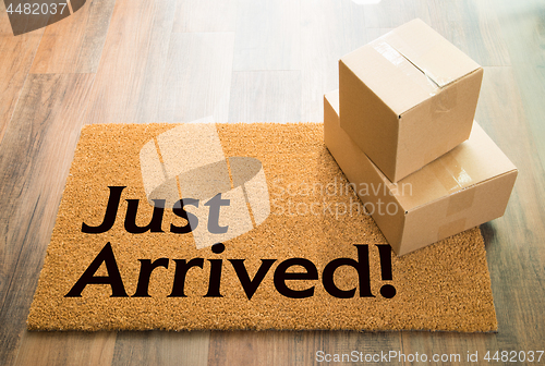 Image of Just Arrived Welcome Mat On Wood Floor With Shipment of Boxes