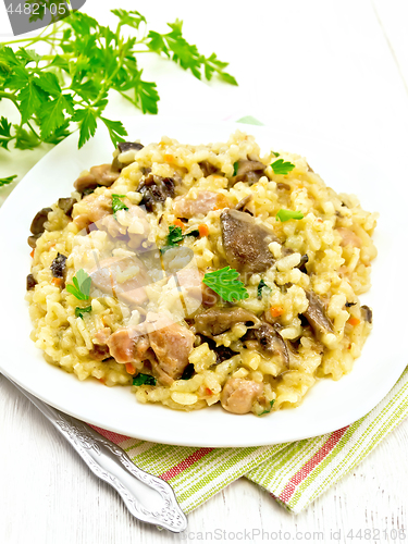 Image of Risotto with mushrooms and chicken on wooden table