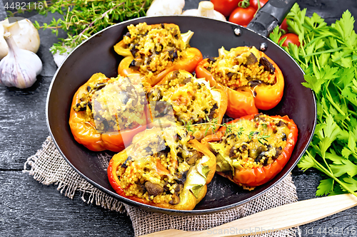 Image of Pepper stuffed with mushrooms and couscous in old pan on burlap