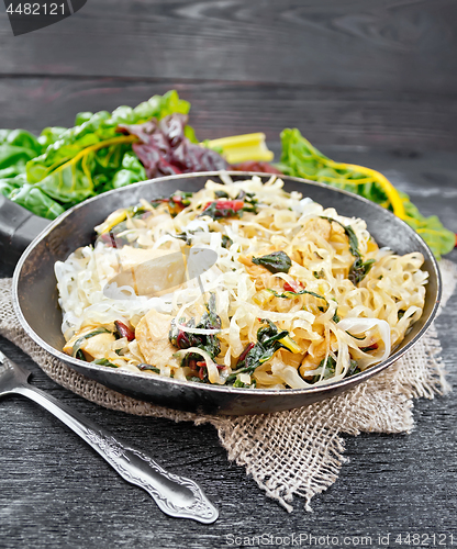 Image of Funchoza with chard and meat in pan on table