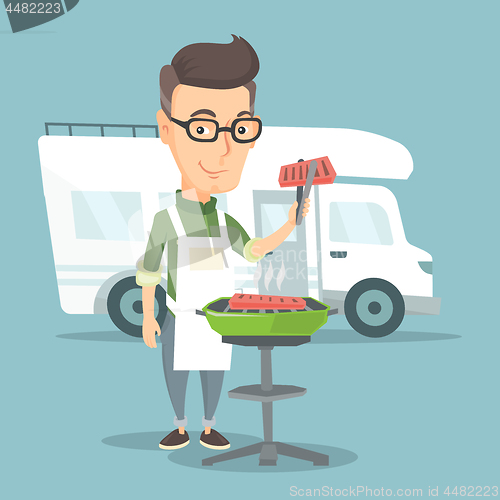 Image of Man having barbecue in front of camper van.