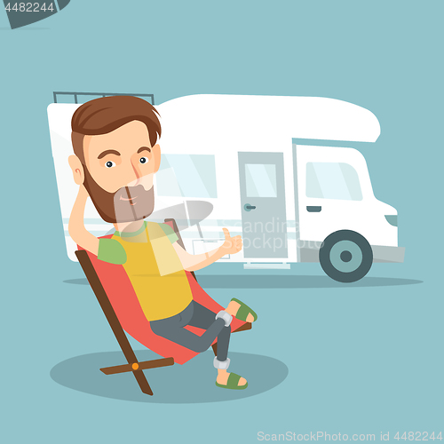 Image of Man sitting in chair in front of camper van.