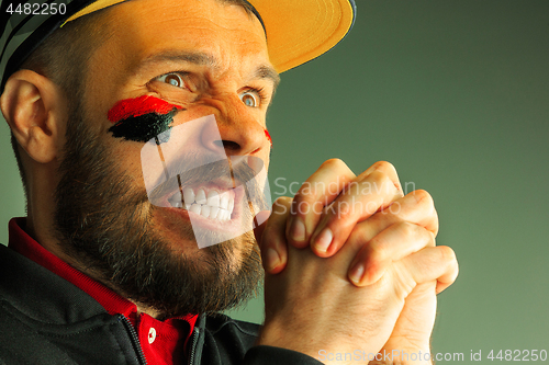 Image of Portrait of a man with the flag of the Germany painted on him face.