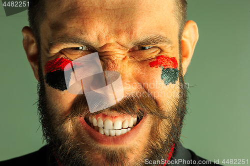 Image of Portrait of a man with the flag of the Germany painted on him face.