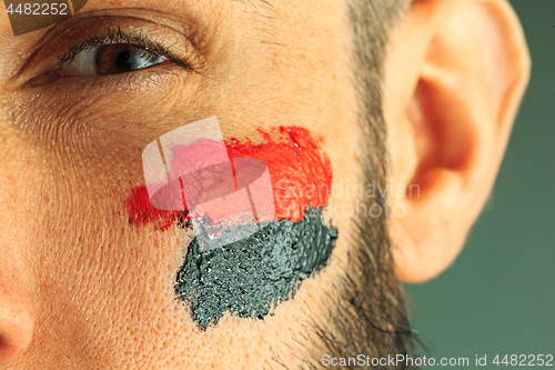 Image of Portrait of a man with the flag of the Germany painted on him face.