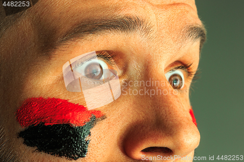 Image of Portrait of a man with the flag of the Germany painted on him face.