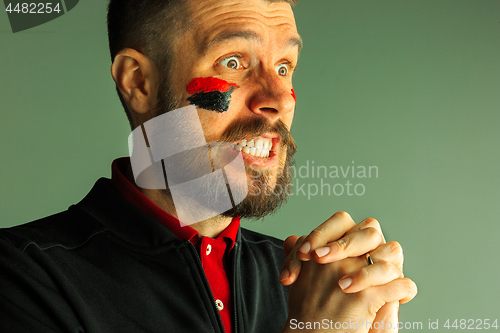 Image of Portrait of a man with the flag of the Germany painted on him face.