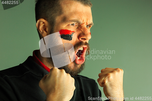 Image of Portrait of a man with the flag of the Germany painted on him face.