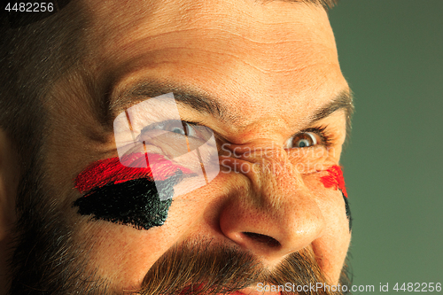 Image of Portrait of a man with the flag of the Germany painted on him face.