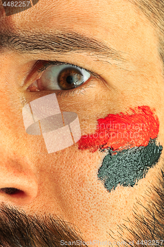 Image of Portrait of a man with the flag of the Germany painted on him face.