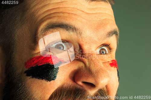 Image of Portrait of a man with the flag of the Germany painted on him face.