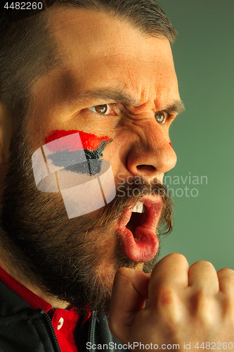 Image of Portrait of a man with the flag of the Germany painted on him face.