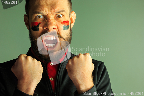 Image of Portrait of a man with the flag of the Germany painted on him face.