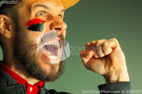 Image of Portrait of a man with the flag of the Germany painted on him face.