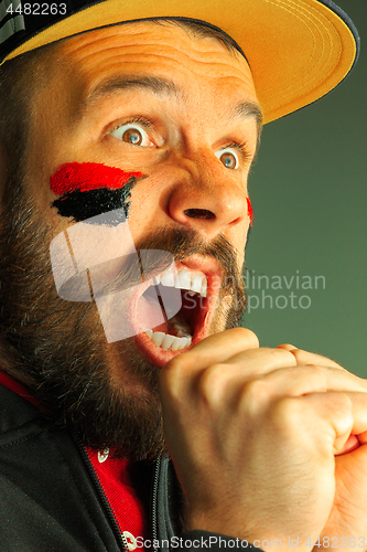 Image of Portrait of a man with the flag of the Germany painted on him face.