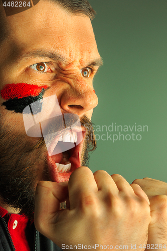 Image of Portrait of a man with the flag of the Germany painted on him face.