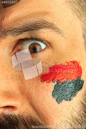 Image of Portrait of a man with the flag of the Germany painted on him face.