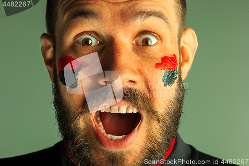 Image of Portrait of a man with the flag of the Germany painted on him face.