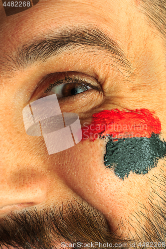 Image of Portrait of a man with the flag of the Germany painted on him face.