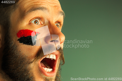 Image of Portrait of a man with the flag of the Germany painted on him face.