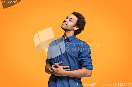Image of The happy business man standing and smiling against orange background.