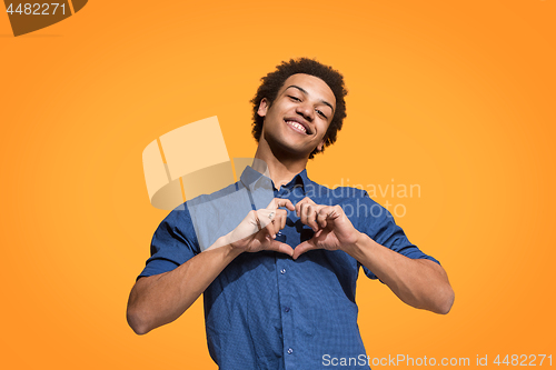 Image of The happy business man standing and smiling against orange background.