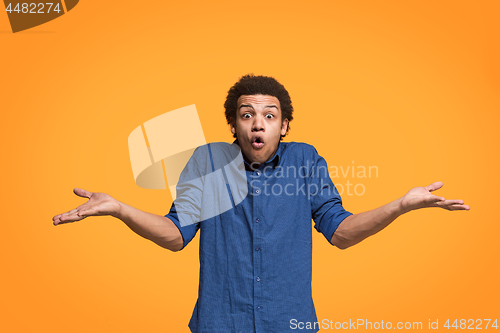Image of The young attractive man looking suprised isolated on orange