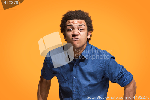 Image of The young emotional angry man screaming on orange studio background