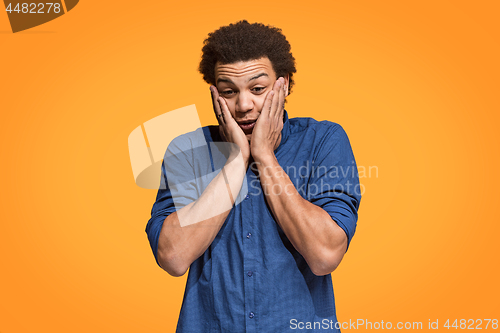 Image of Handsome man looking suprised isolated on orange