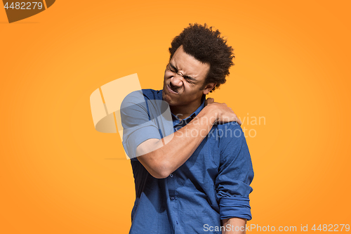 Image of Young man overwhelmed with a pain in the shoulder.