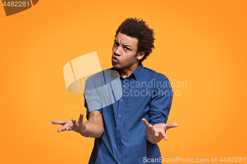 Image of Beautiful male half-length portrait isolated on orange studio backgroud. The young emotional afro man