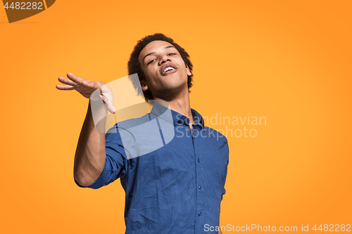 Image of Beautiful male half-length portrait isolated on orange studio backgroud. The young emotional surprised man