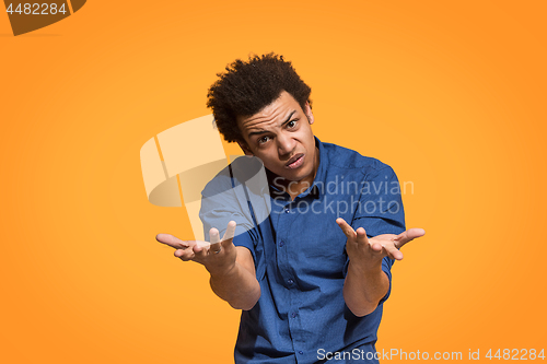 Image of Beautiful male half-length portrait isolated on orange studio backgroud. The young emotional afro man