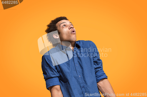 Image of Let me think. Doubtful pensive man with thoughtful expression making choice against orange background