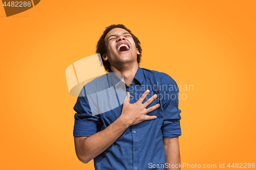 Image of The happy business man standing and smiling against orange background.