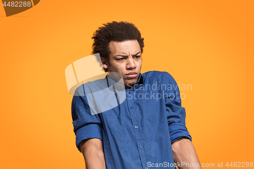 Image of Let me think. Doubtful pensive man with thoughtful expression making choice against orange background