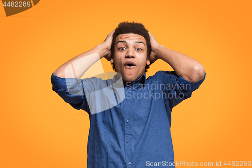 Image of The young attractive man looking suprised isolated on orange