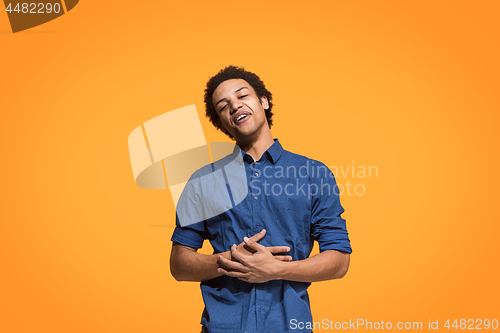 Image of The happy business man standing and smiling against orange background.