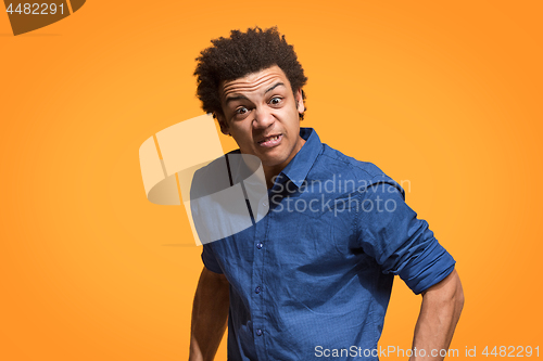 Image of The young emotional angry man screaming on orange studio background