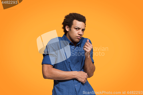 Image of Let me think. Doubtful pensive man with thoughtful expression making choice against orange background